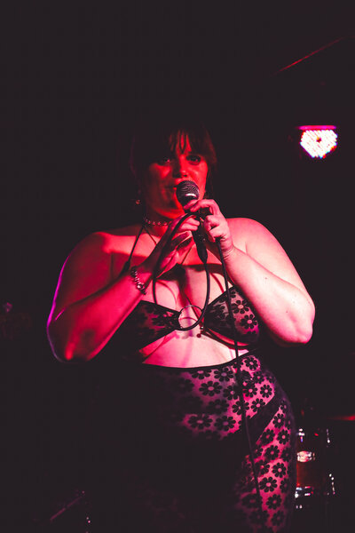 Madeline sings on stage, bathed in red light.