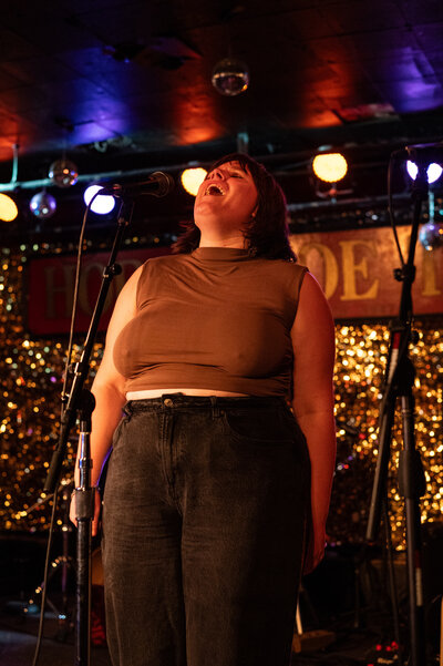 Madeline sings on stage, leaning back and closing her eyes.